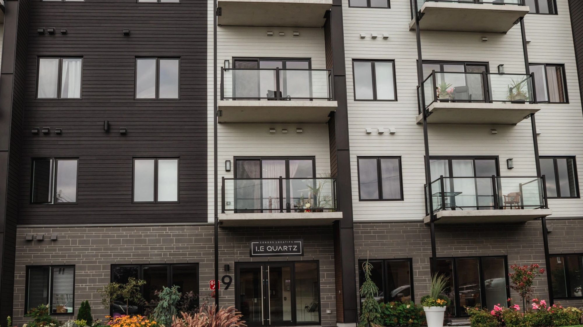 La façade du Quartz, condos locatifs au 9, rue Chatel à Victoriaville : parement sombre et blanc, balcons de verre, l'enseigne au-dessus de l'entrée